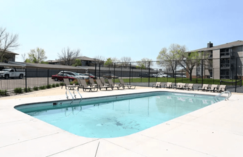 A swimming pool with a fence and chairs around it.
